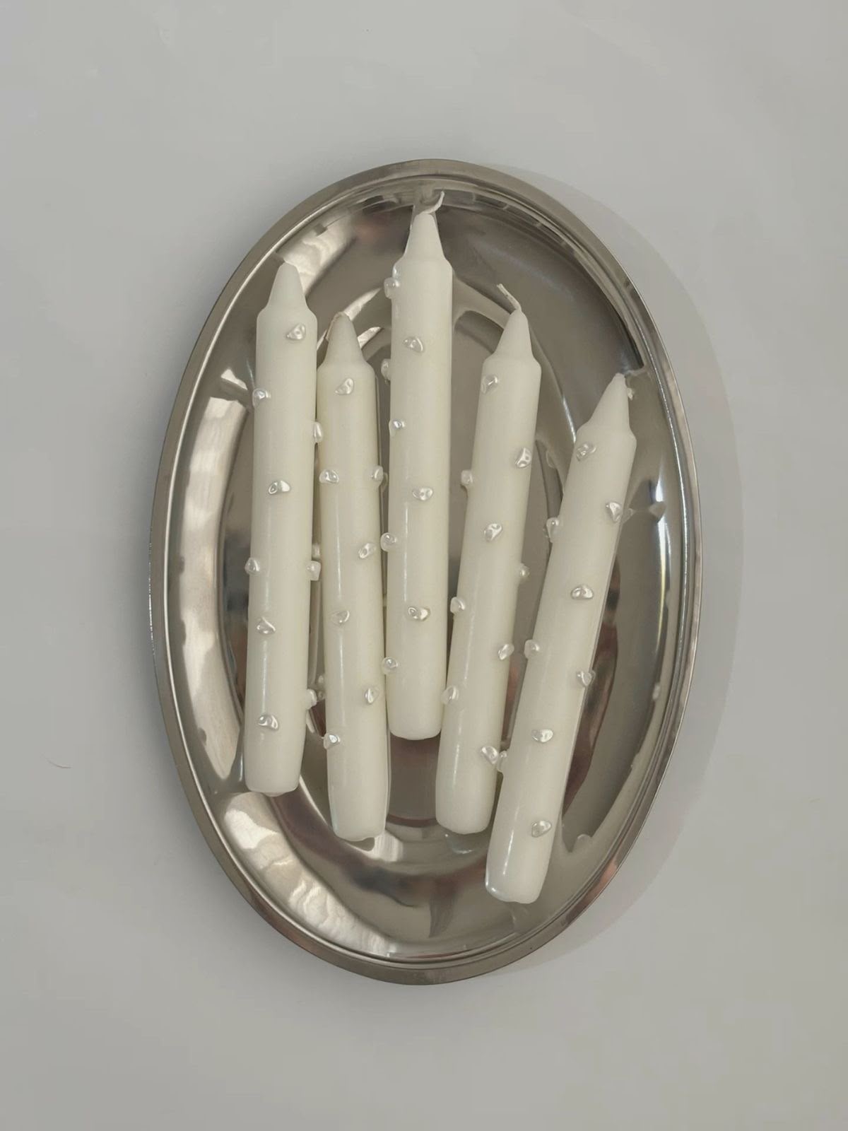 Velas blancas decoradas sobre bandeja metálica
